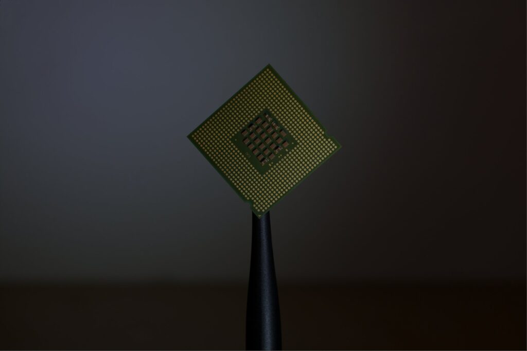 A computer processor chip balanced on the tip of a stylus.