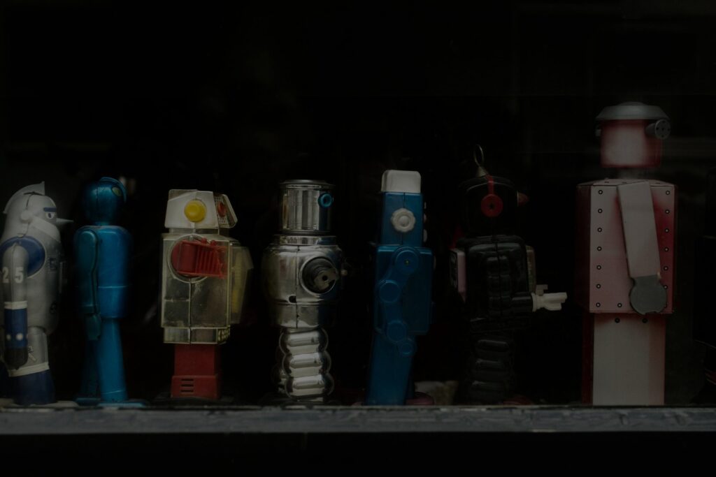 A row of vintage tin toy robots in a dark display case.